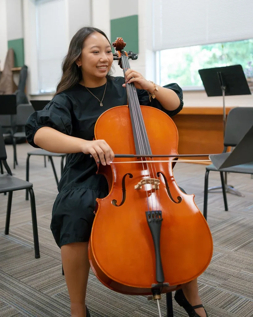 A student plays the cello, using the bow and fingerboard.