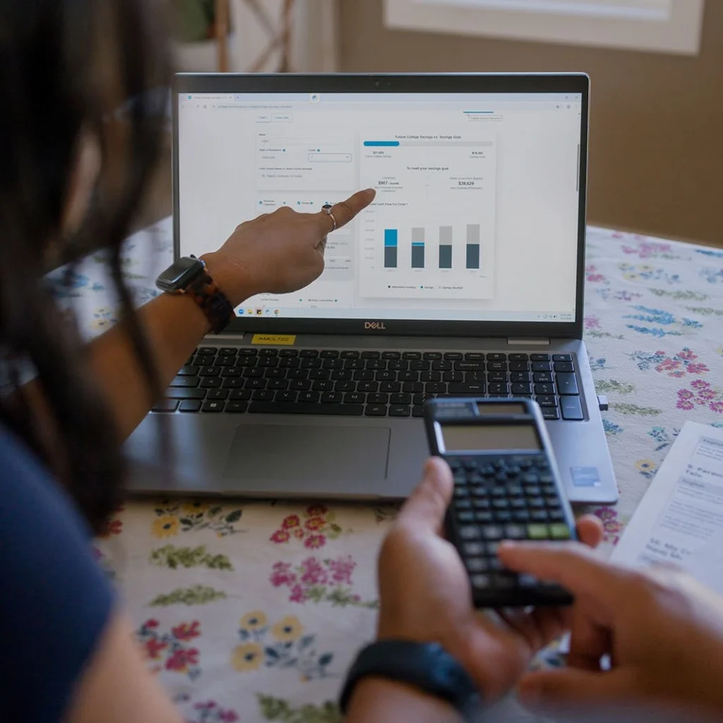 An adult points to a financial chart while using a calculator.
