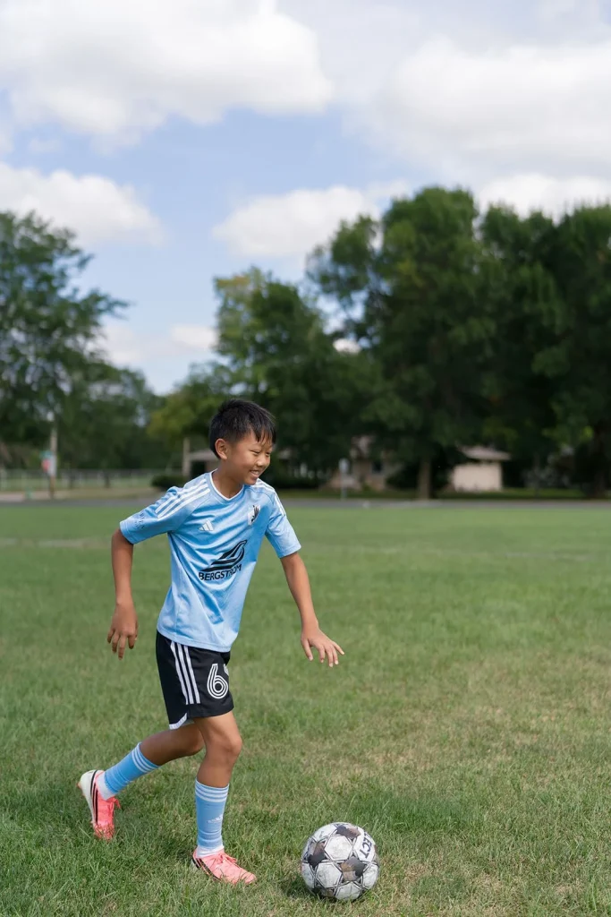 A student plays soccer outdoors.