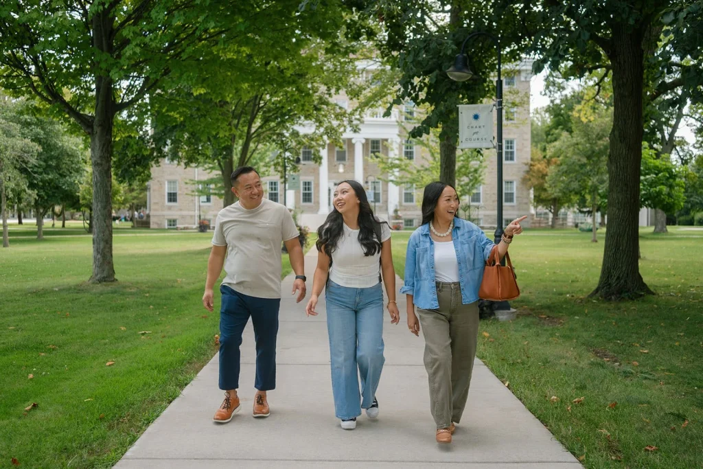 A student and two adults walking together on a college campus.