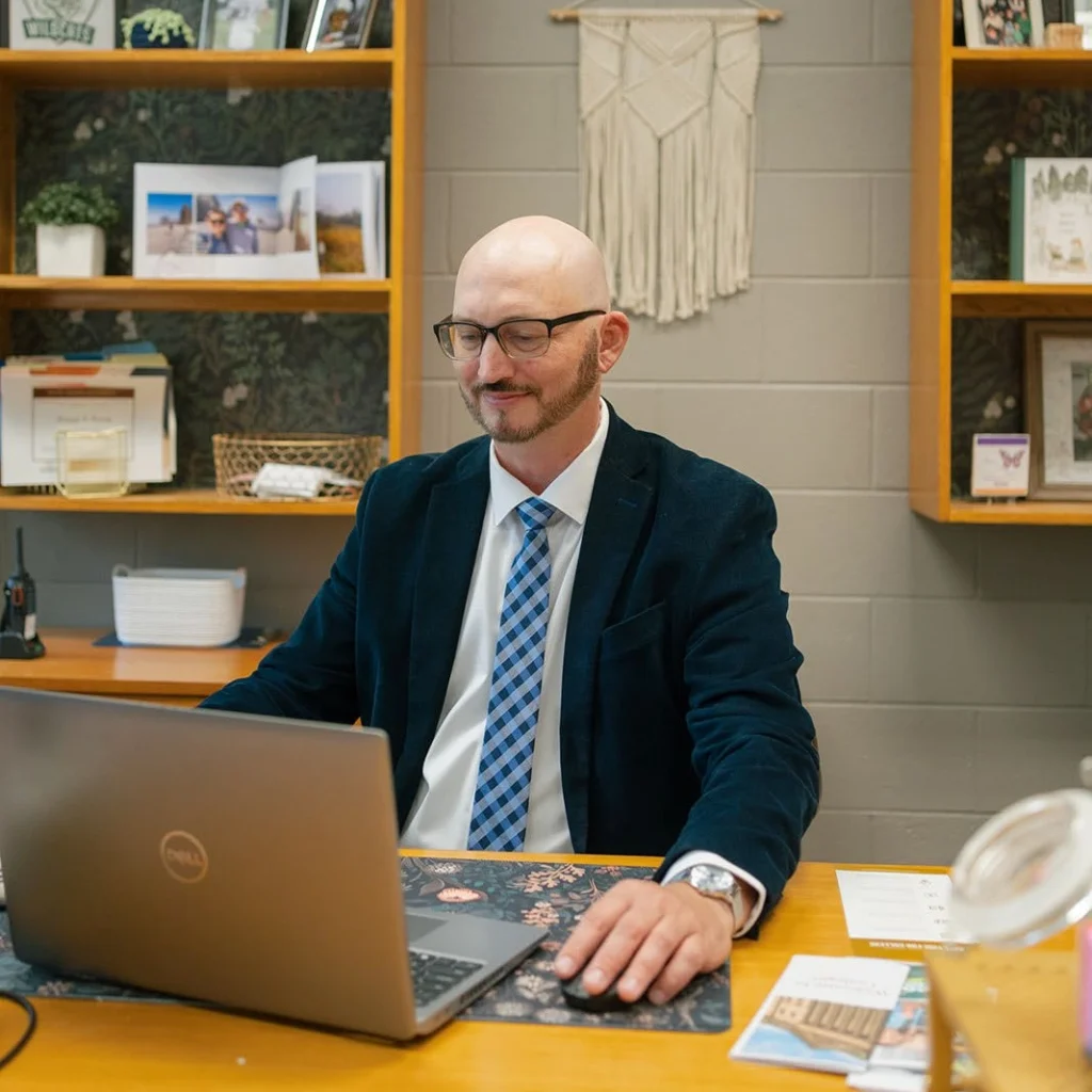 An adviser reviews information at a laptop.