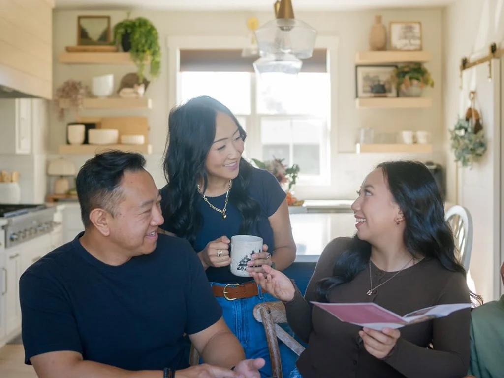 A student and two adults discuss a document at home.